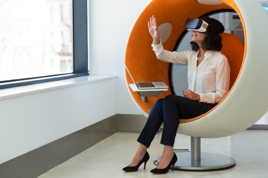 a woman sitting on a chair wearing a VR goggle